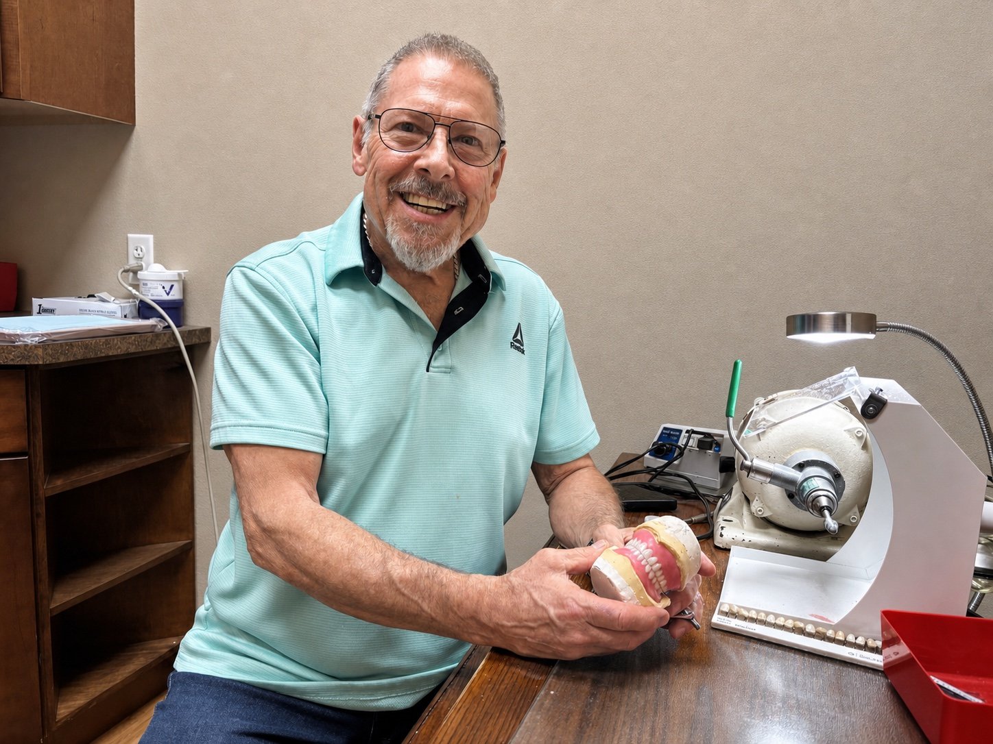 Star Dental's on-site denture technician holding a denture model beside laboratory equipment